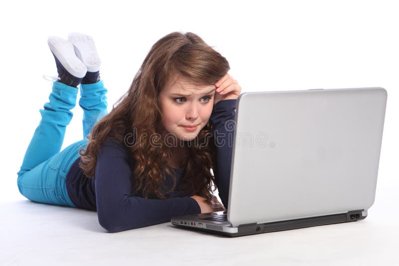 Worried young high school teenager girl lying on the floor looking confused and frightened while surfing the internet on laptop, reading bad news. Worried young high school teenager girl lying on the floor looking confused and frightened while surfing the internet on laptop, reading bad news.