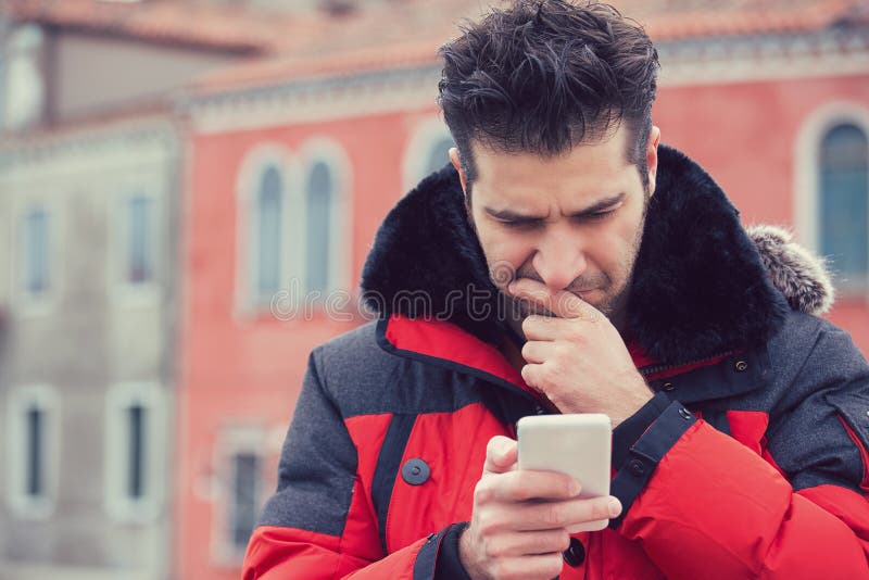 Confused upset man looking at his mobile phone standing outdoors stock images Confused upset man looking at his mobile phone standing outdoors stock images