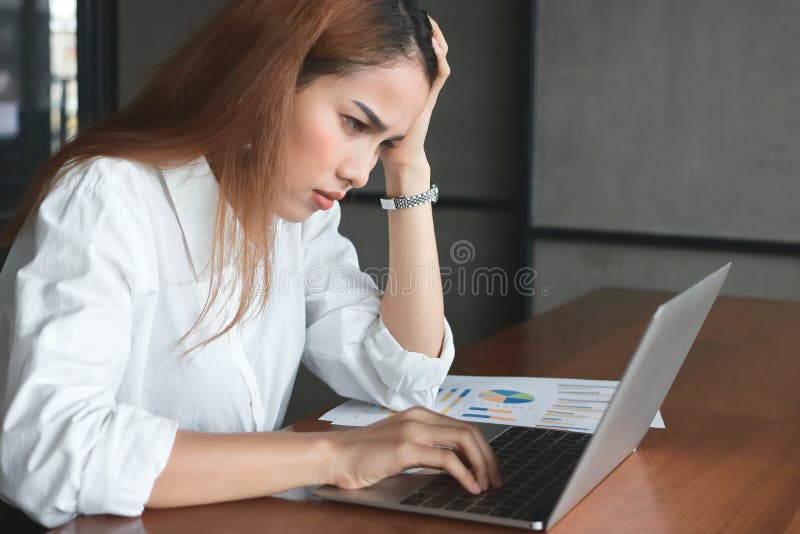 Confused upset young Asian business woman suffering from severe from depression in workplace.