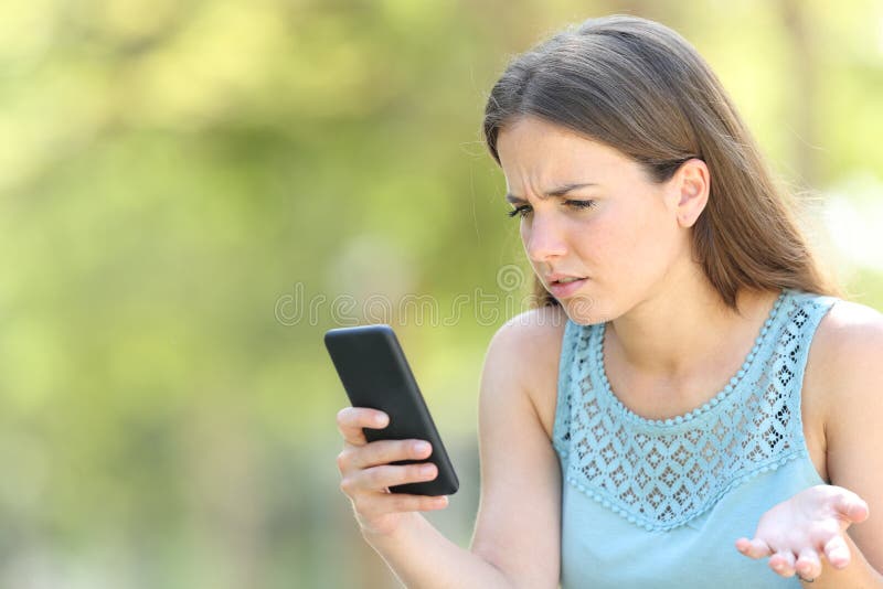 Confused woman checking smart phone on green