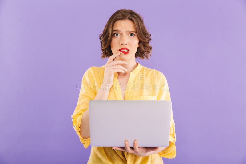 Confused woman isolated over purple wall background using laptop computer.