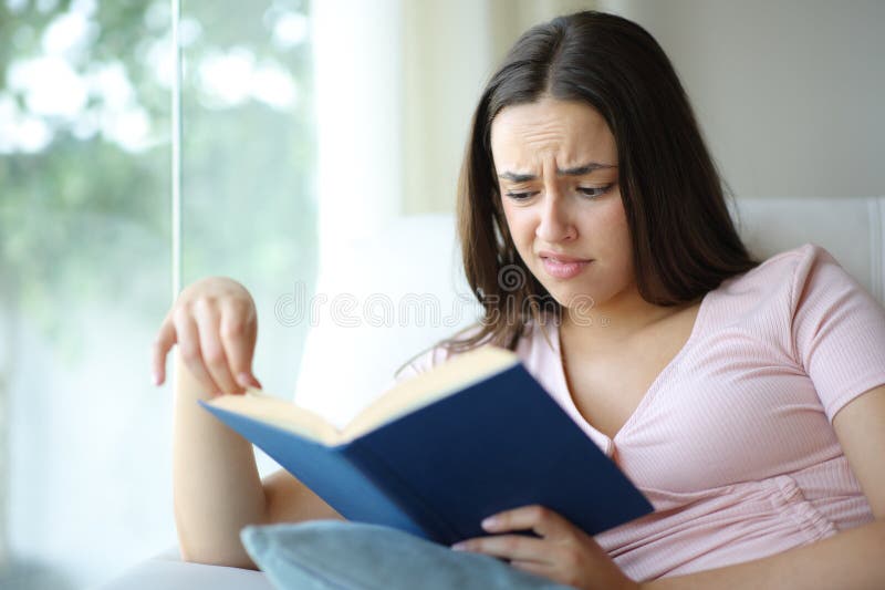 Confused woman reading a paper book at home stock images