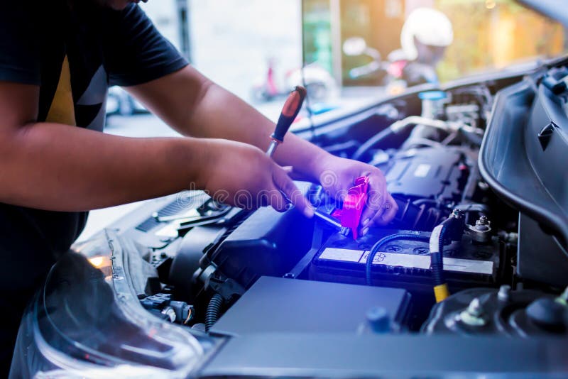 Confuso dell'accumulatore per di automobile cambiante del meccanico maschio, accumulatore per di automobile della riparazione del immagini stock libere da diritti Confuso dell'accumulatore per di automobile cambiante del meccanico maschio, accumulatore per di automobile della riparazione del immagini stock libere da diritti