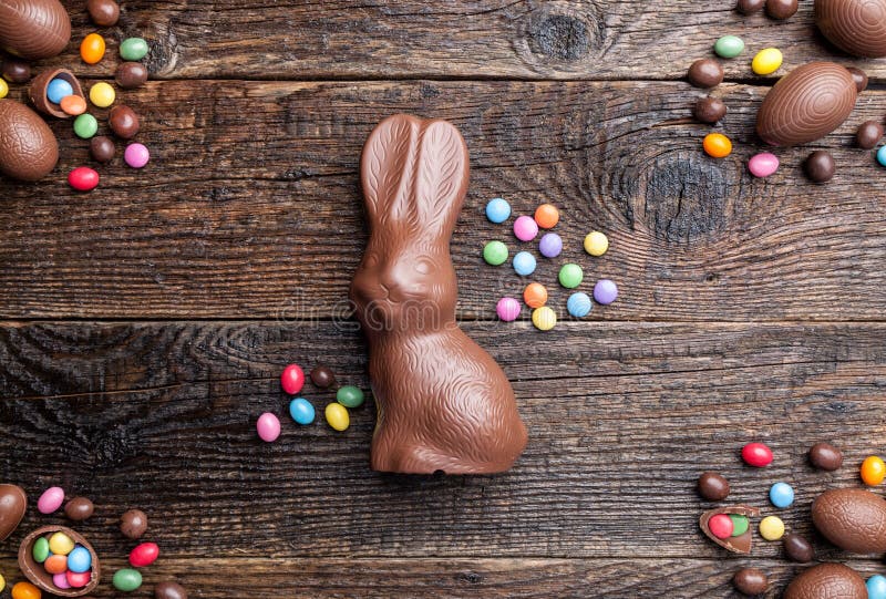 Coniglietto, uova e dolci di pasqua del cioccolato su fondo rustico