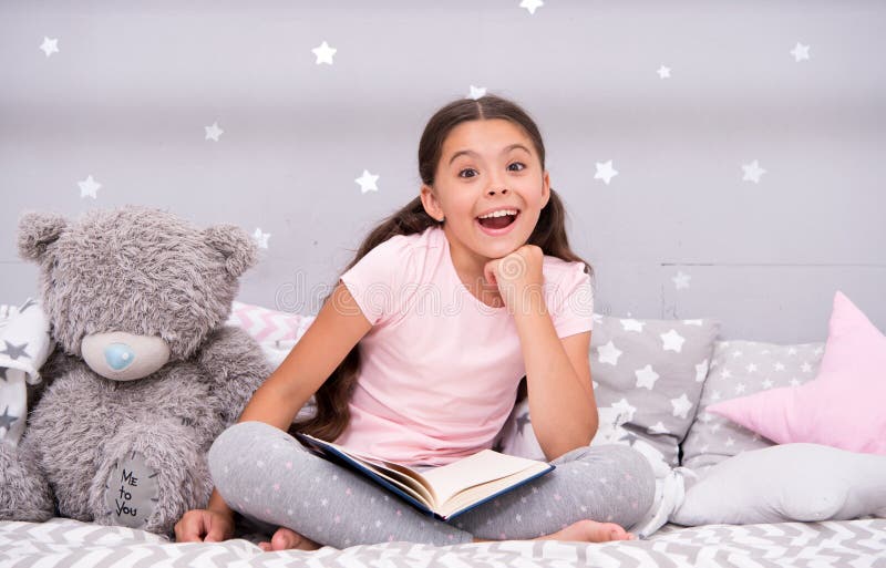 Conjeture su cuento de hadas preferido El niño de la muchacha sienta la cama con el libro leído del oso de peluche El niño se pre imagenes de archivo Conjeture su cuento de hadas preferido El niño de la muchacha sienta la cama con el libro leído del oso de peluche El niño se pre imagenes de archivo