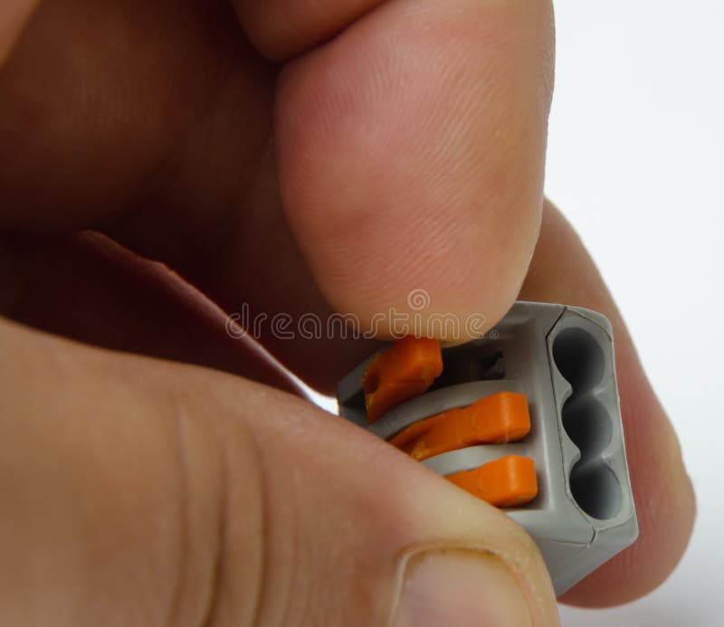 Connector for splicing all types of wires 3-wire with levers in a gray housing in the hand between three fingers stock photo