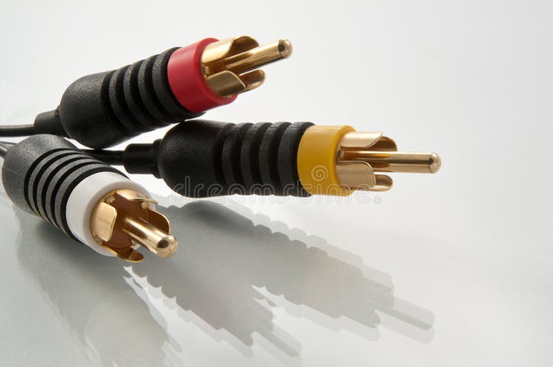 Close up from a low angle of red, yellow and white AV cable connectors against white with reflection in foreground. Close up from a low angle of red, yellow and white AV cable connectors against white with reflection in foreground.