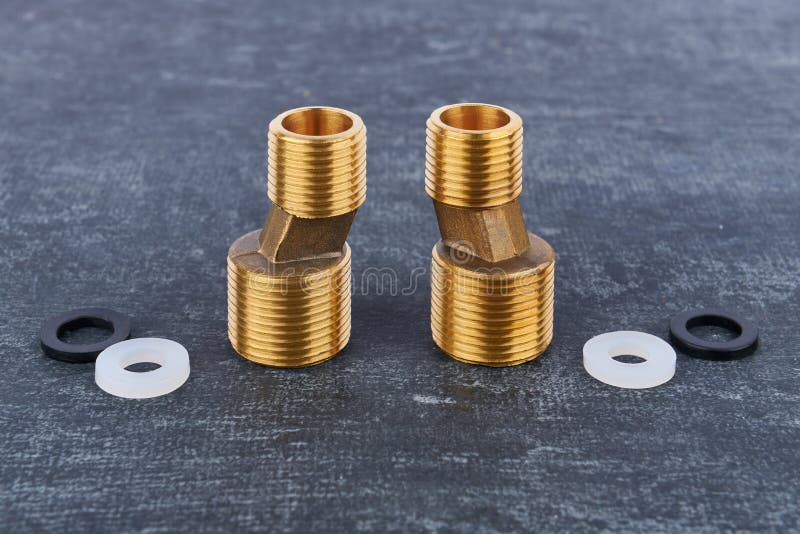 Brass eccentric connectors for the wall water mixer tap installation closeup on a gray background, shallow depth of sharpness. Brass eccentric connectors for the wall water mixer tap installation closeup on a gray background, shallow depth of sharpness