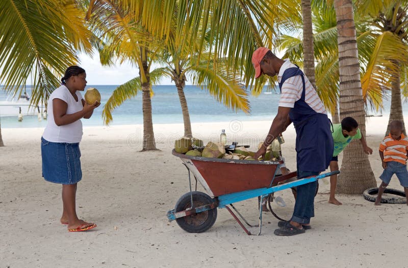 Coconut fruit vendor at the Saona beach, Saona island, and woman who is drinking from the coconut. Saona Island is a tropical island located a short distance from the mainland on the south-east tip of the Dominican Republic, Hispaniola island. It is a government protected nature reserve and is part of East National Park. Coconut fruit vendor at the Saona beach, Saona island, and woman who is drinking from the coconut. Saona Island is a tropical island located a short distance from the mainland on the south-east tip of the Dominican Republic, Hispaniola island. It is a government protected nature reserve and is part of East National Park