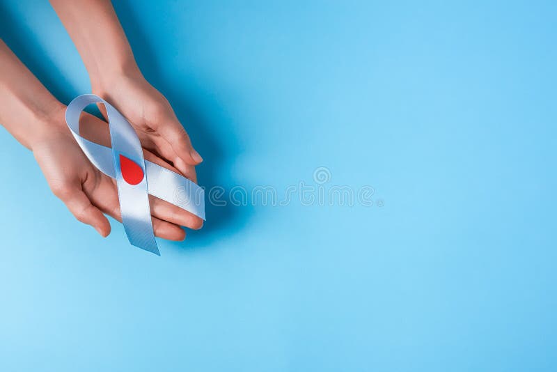 Consapevolezza del nastro blu con calo rosso sangue nelle mani della donna su un fondo blu, giornata mondiale del diabete immagini stock libere da diritti Consapevolezza del nastro blu con calo rosso sangue nelle mani della donna su un fondo blu, giornata mondiale del diabete immagini stock libere da diritti