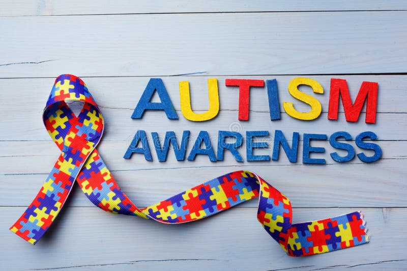 Consapevolezza di autismo del mondo e giorno o mese di orgoglio con il nastro del modello di puzzle su fondo di legno blu