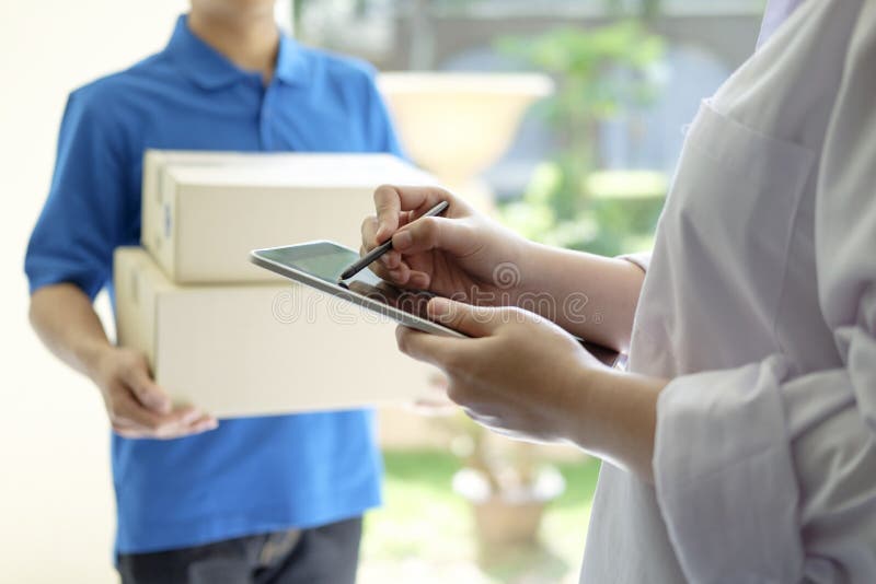 delivery, mail, people and shipping concept.Young woman sign in digital mobile phone after receiving parcel from courier at home. delivery, mail, people and shipping concept.Young woman sign in digital mobile phone after receiving parcel from courier at home.