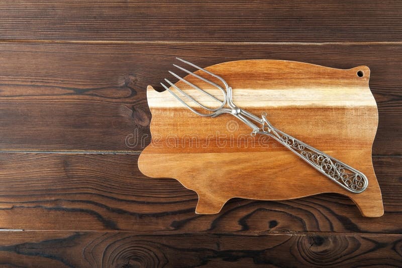 Conseil en bois sous forme de porc avec une fourchette pour la viande Porc faisant cuire le concept sur une table de texture images libres de droits Conseil en bois sous forme de porc avec une fourchette pour la viande Porc faisant cuire le concept sur une table de texture images libres de droits