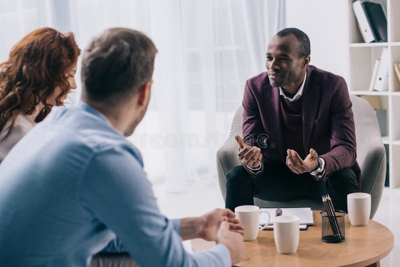 Conselheiro afro-americano de sorriso que fala aos pares novos foto de stock Conselheiro afro-americano de sorriso que fala aos pares novos foto de stock