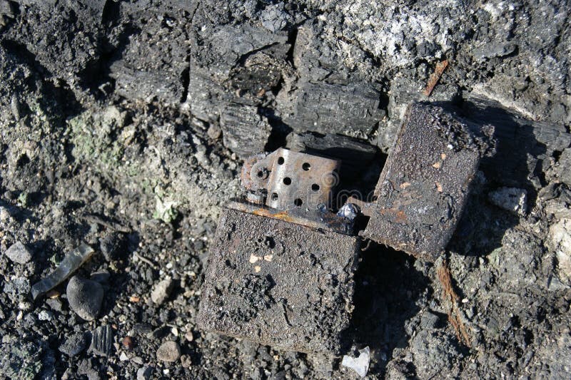 Consequences of the Fire. Burnt Metal Lighter in Ashes. Stock Image
