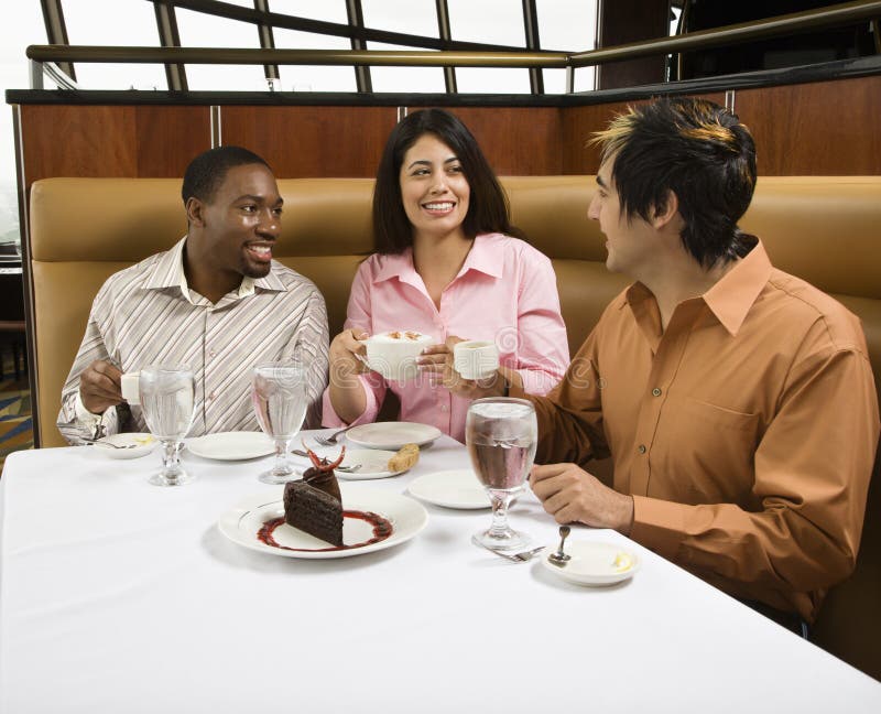 Small group of mid adult friends at restaurant talking and having dessert. Small group of mid adult friends at restaurant talking and having dessert.