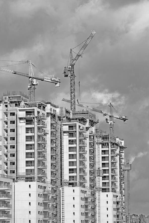 Construction work of high-rise residential buildings.Active construction of the housing complex, with the working cranes .Black and White. Construction work of high-rise residential buildings.Active construction of the housing complex, with the working cranes .Black and White