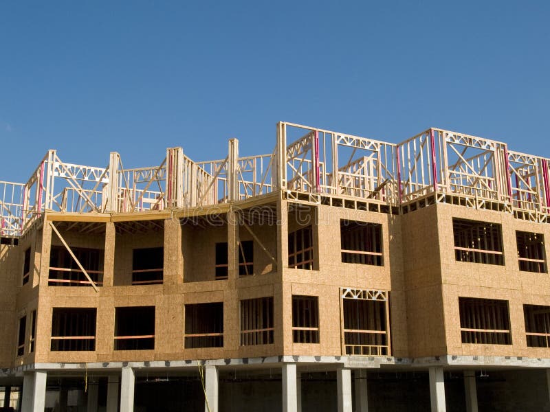 Urban construction site under a blue sky with white clouds. Woodframe on a concrete substructure. Urban construction site under a blue sky with white clouds. Woodframe on a concrete substructure.