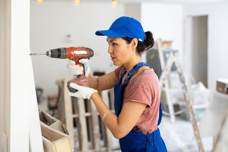Construcción de mujeres usando taladro para perforar la pared foto de archivo libre de regalías