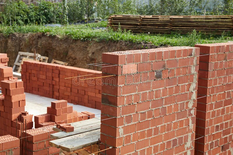 Constructed wall made of red clay bricks is being laid in a pattern. stock photo