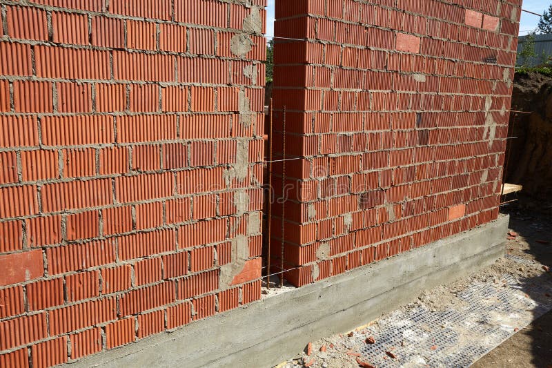Constructed wall made of red clay bricks is being laid in a pattern. stock photography