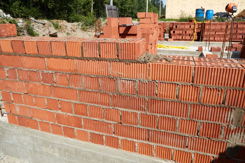 Constructed wall made of red clay bricks is being laid in a pattern. royalty free stock photography