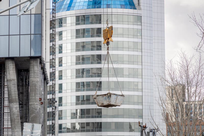 Construction of Buildings. a Crane Lifts a Container with Concrete