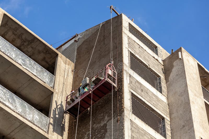 Construction Cradle Hanging at the Wall of a House Under Construction