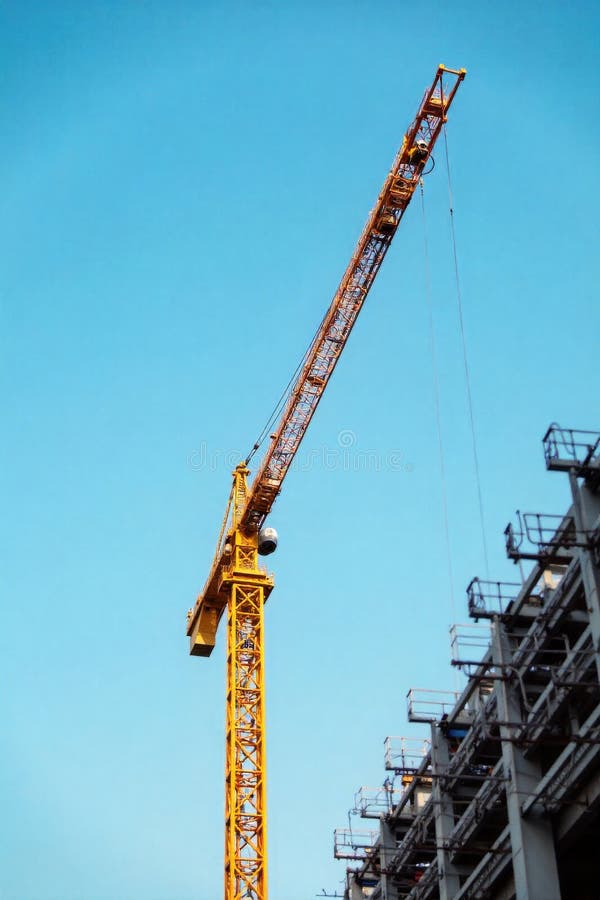 Construction crane lifting beams for a multi story residential building, symbolizing growth and development. A large yellow royalty free illustration