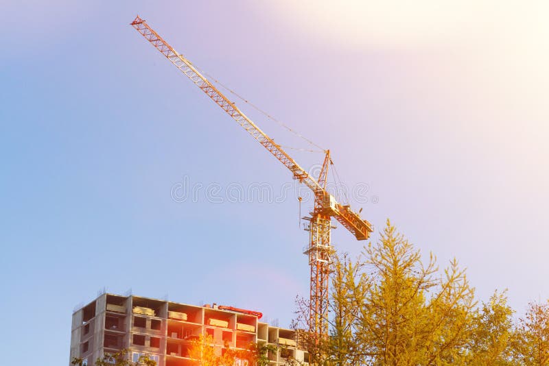 Construction Crane Towers Over House Under Construction Against Blue