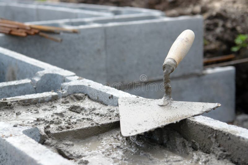 Closeup of mason's trowel on concrete shuttering blocks filled with mortar. Closeup of mason's trowel on concrete shuttering blocks filled with mortar