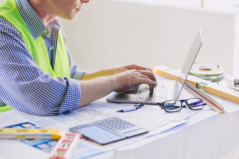 Construction engineer builder working at desk typing on laptop computer. People using mobility 5G Internet wireless connection stock photo