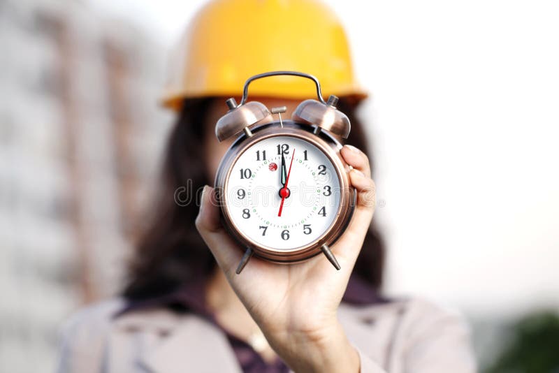 Construction engineer holding alarm clock