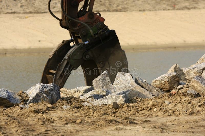 Buck hoe construction equipment working on a river dike. Track hoe construction excavator stock images, royalty-free photos and pictures