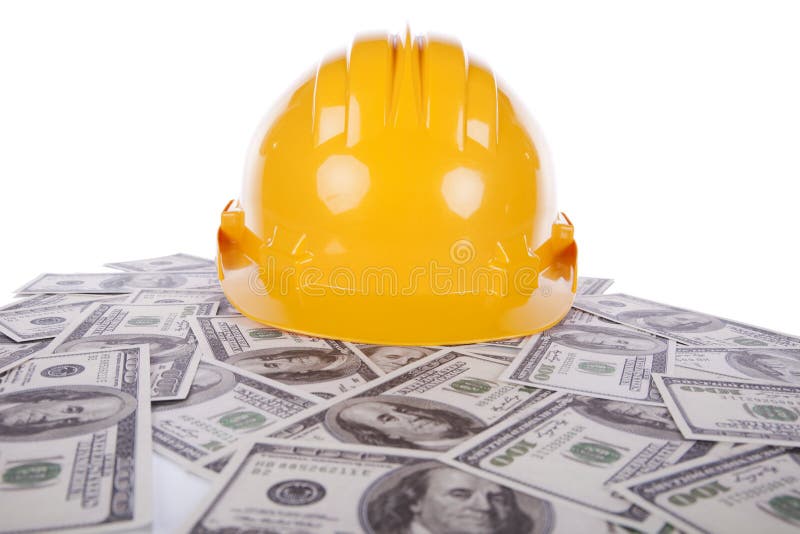 Construction yellow helmet over many dollar bills. Construction yellow helmet over many dollar bills