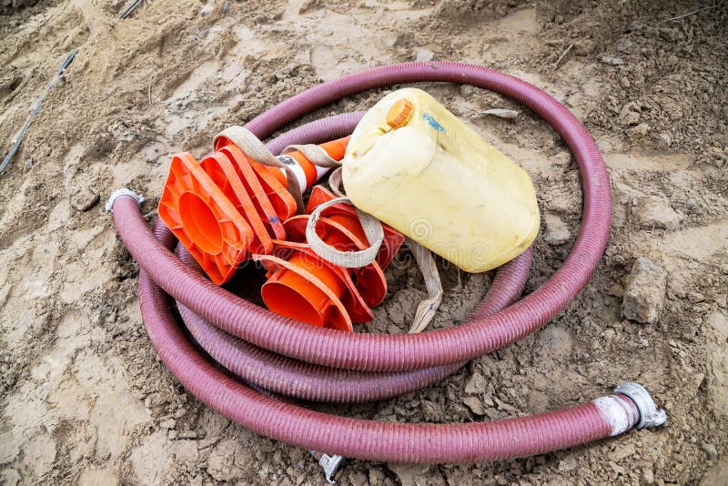 Construction Hose, Water Canister and Orange Cones are on the Ground