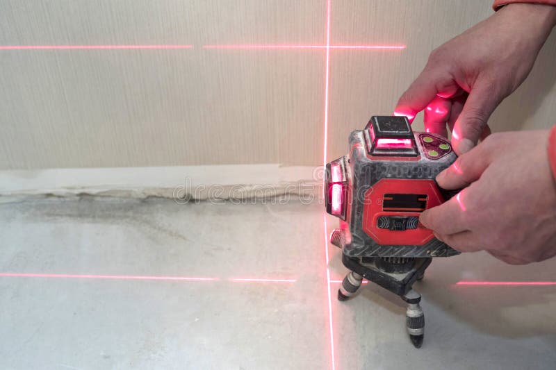 Construction laser level and the hands of a worker. The builder measures the level. Repair concept.