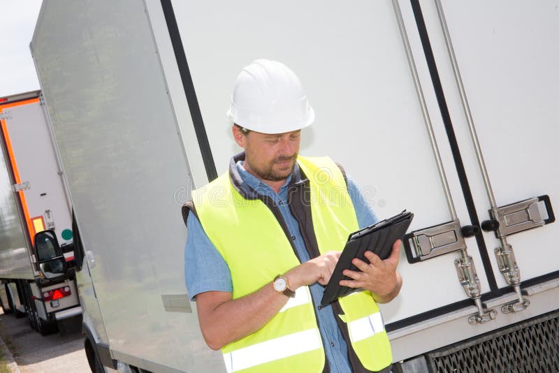 Construction man worker operating touch pad device tablet front of rear truck