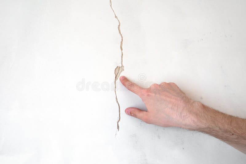 Construction man worker repairing a crack wall of a home, plastering cement on wall. Builder applying white cement to a