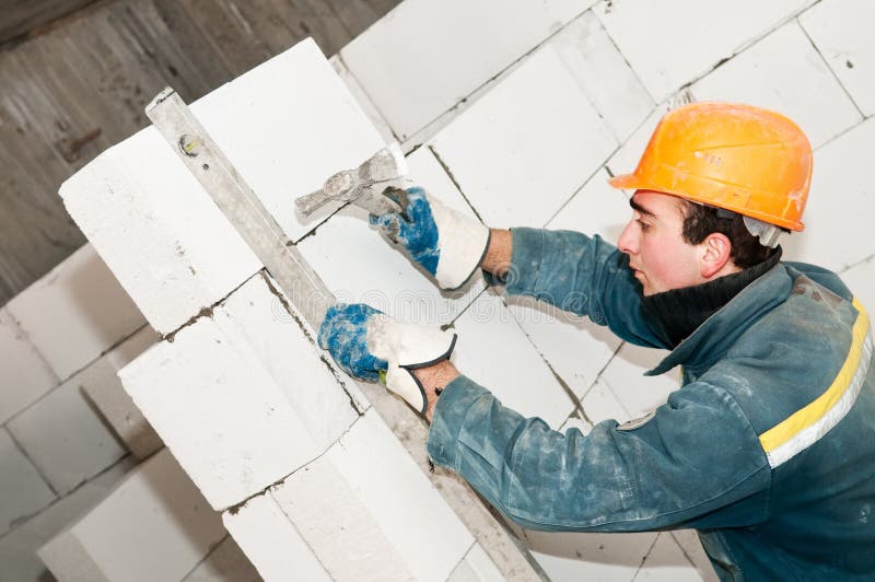 Construction mason worker bricklayer checking a brickwork with level tube