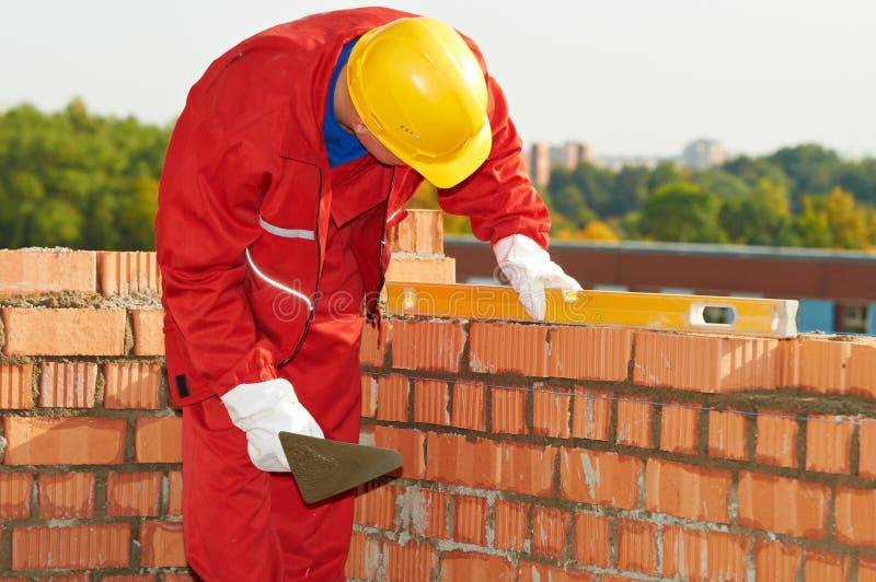 Construction mason worker bricklayer making a brickwork with trowel and cemant mortar