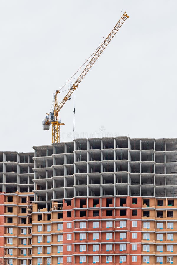 Construction of a modern residential high-rise building with a crane. Construction crane and building on the sky