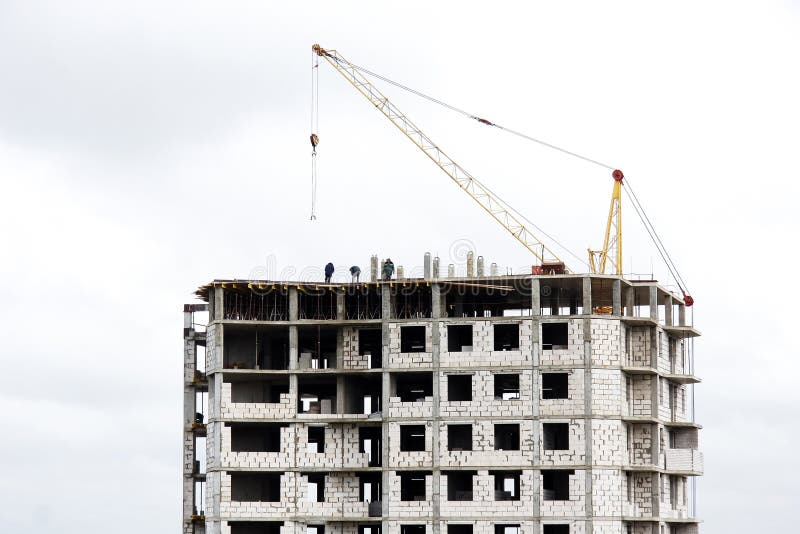 The construction of a multi-storey building of brick and concrete. Fragment of a modern house and a construction crane. Close-up. Concrete fragment stock images, royalty-free photos and pictures