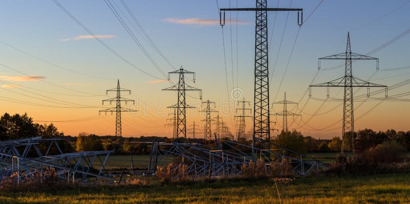 Components for new electrictiy pylons on a meadow with old pylons in the background at sunset. Red pylons stock images, royalty-free photos and pictures