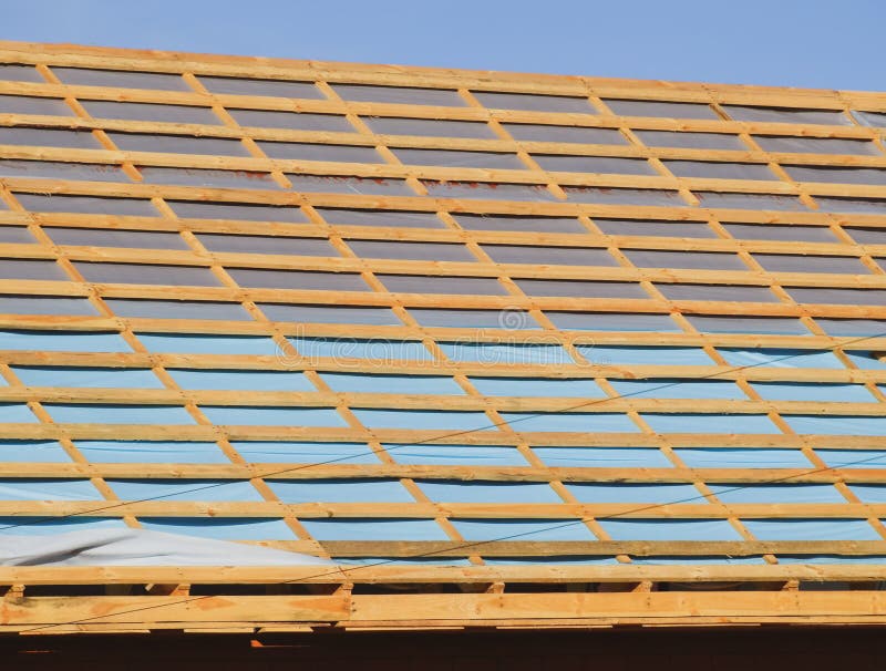 Construction of the roof of a new house. Wooden bars and vapor barrier under the corrugated metal profile