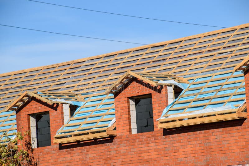 Construction of the roof of a new house. Wooden bars and vapor barrier under the corrugated metal profile