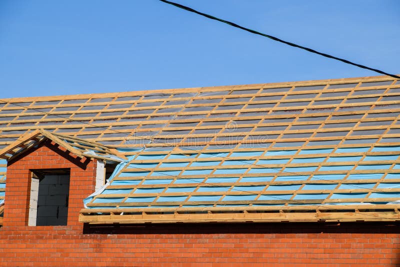 Construction of the roof of a new house. Wooden bars and vapor barrier under the corrugated metal profile