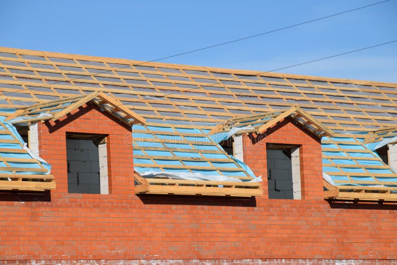 Construction of the roof of a new house. Wooden bars and vapor barrier under the corrugated metal profile