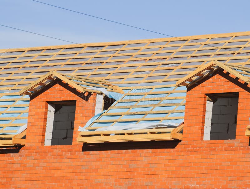 Construction of the roof of a new house. Wooden bars and vapor barrier under the corrugated metal profile