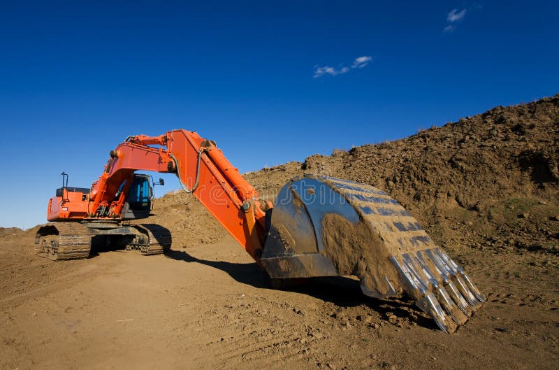 A large orange backhoe at a construction site. Claw machine stock images, royalty-free photos and pictures
